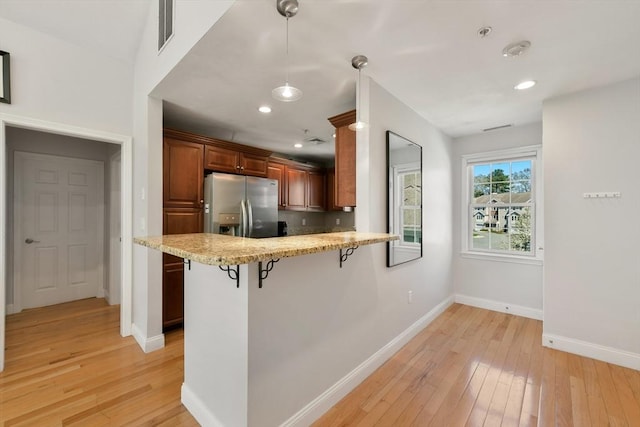 410 Salem St Unit 707, Wakefield, MA 01880 - kitchen with stainless steel fridge with ice dispenser, a kitchen breakfast bar, light wood-style floors, baseboards, and hanging light fixtures