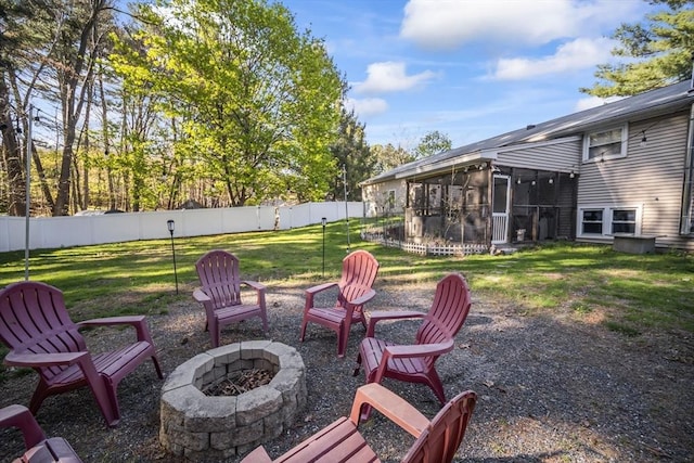 view of yard featuring a sunroom, a fenced backyard, and a fire pit