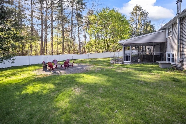 view of yard with a fenced backyard, a sunroom, and an outdoor fire pit