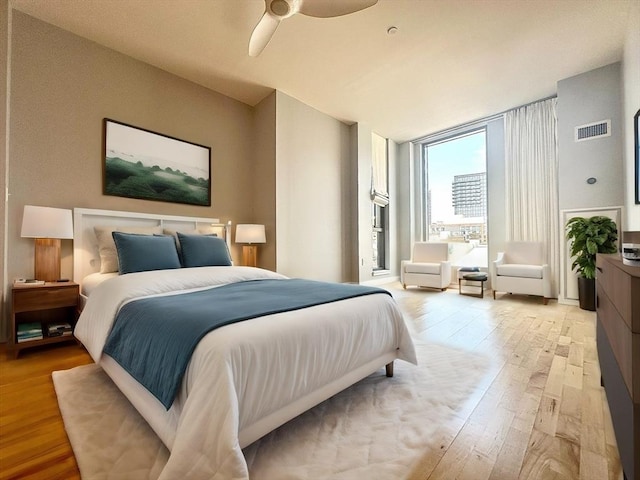 bedroom featuring floor to ceiling windows, ceiling fan, and light wood-type flooring