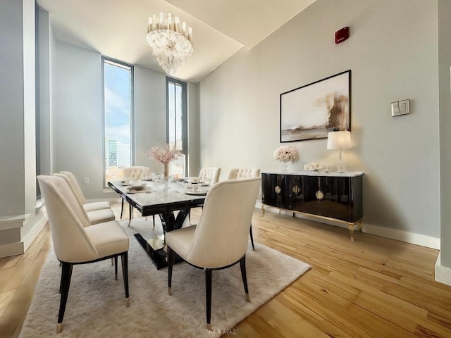 dining area featuring light wood-type flooring, expansive windows, and a notable chandelier