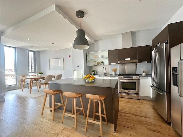 kitchen with a breakfast bar area, hanging light fixtures, light hardwood / wood-style floors, and appliances with stainless steel finishes