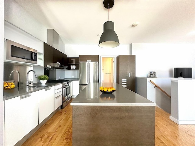 kitchen with pendant lighting, sink, light hardwood / wood-style floors, appliances with stainless steel finishes, and a kitchen island