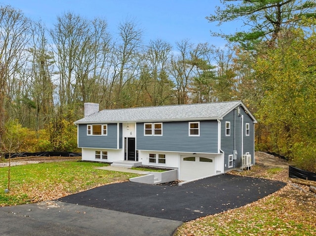 raised ranch with central AC, a garage, and a front lawn