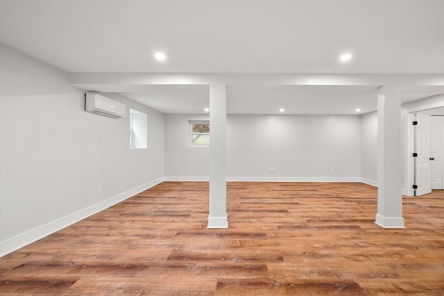 basement featuring a wall mounted AC and light wood-type flooring