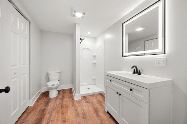 bathroom featuring vanity, hardwood / wood-style floors, toilet, and walk in shower