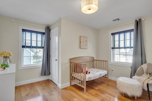 bedroom featuring a crib and light hardwood / wood-style floors