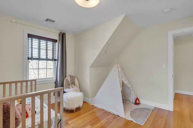 bedroom featuring multiple windows, a nursery area, and light hardwood / wood-style floors