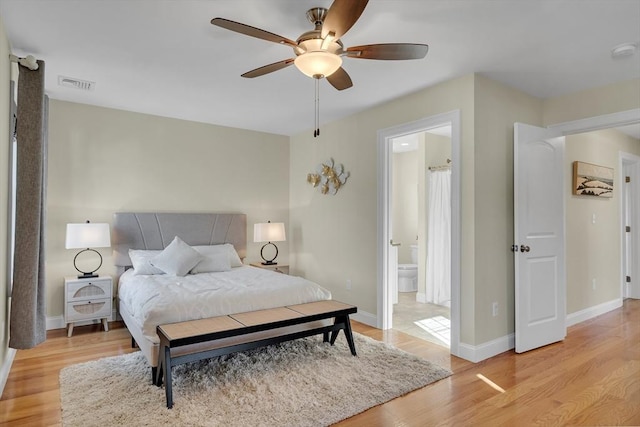 bedroom with light wood-type flooring, ceiling fan, and ensuite bath