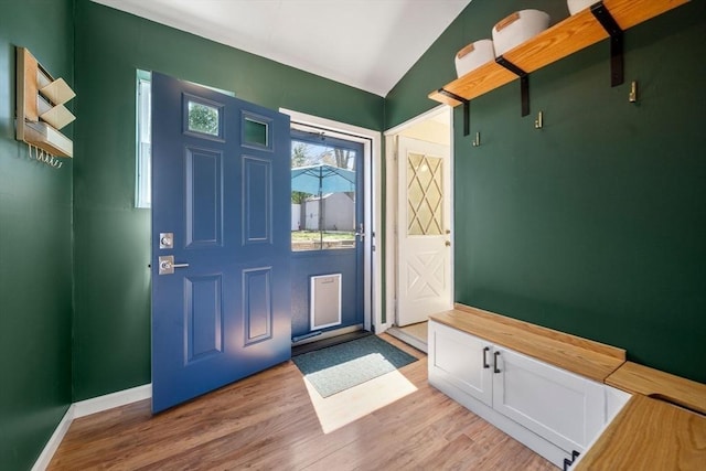 entryway featuring baseboards, vaulted ceiling, and light wood-style floors