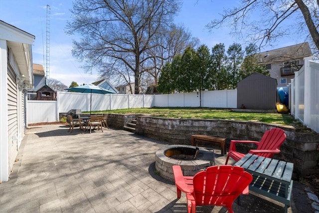 view of patio with a storage shed, a fire pit, outdoor dining area, and a fenced backyard