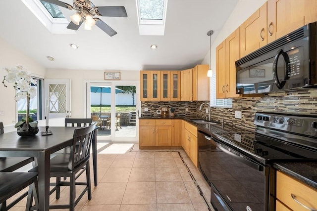 kitchen with a sink, decorative backsplash, black appliances, and a skylight