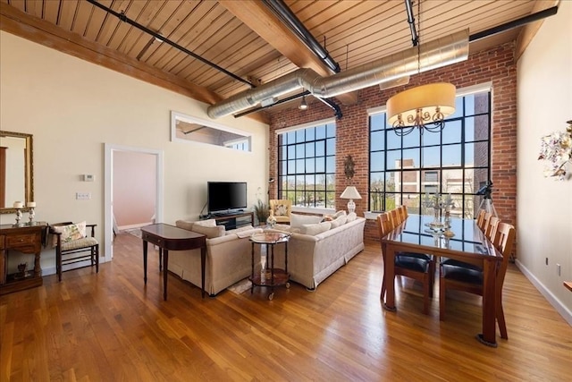 living area featuring wood finished floors, brick wall, and beam ceiling