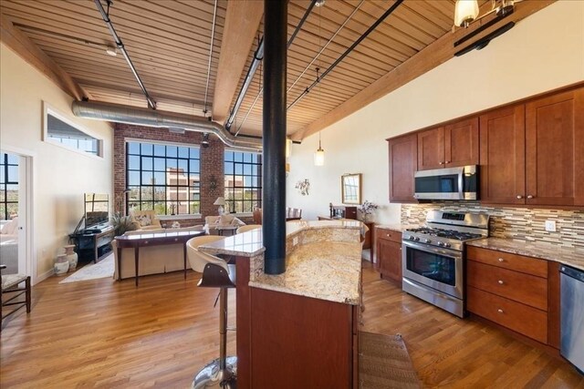 kitchen featuring open floor plan, light wood-style flooring, appliances with stainless steel finishes, and wooden ceiling