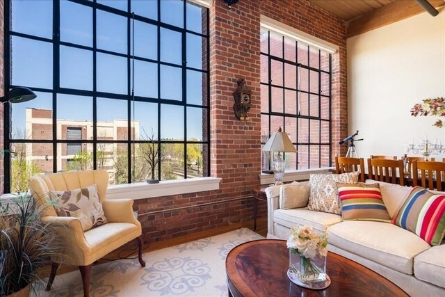 living room featuring brick wall, a healthy amount of sunlight, wood ceiling, and a towering ceiling
