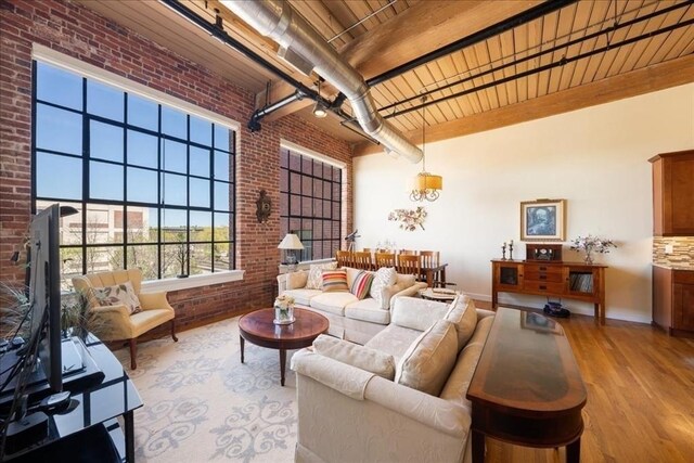 living room featuring brick wall, baseboards, wooden ceiling, wood finished floors, and beamed ceiling