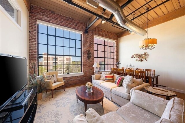 living area featuring wood finished floors, brick wall, beamed ceiling, a high ceiling, and wooden ceiling