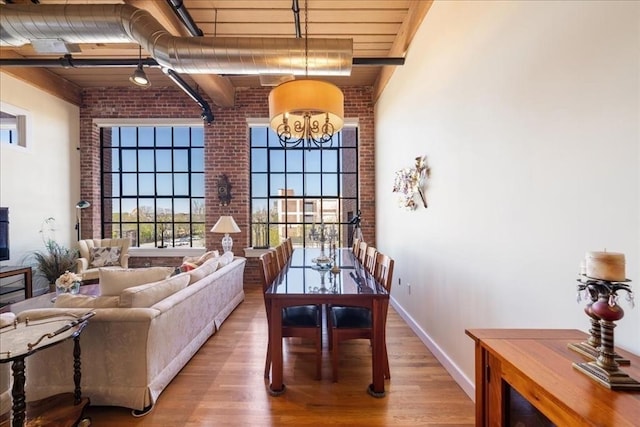 dining area with plenty of natural light, a high ceiling, light wood-type flooring, and brick wall