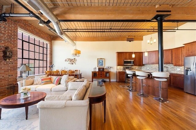 living room featuring a towering ceiling, brick wall, and wood finished floors