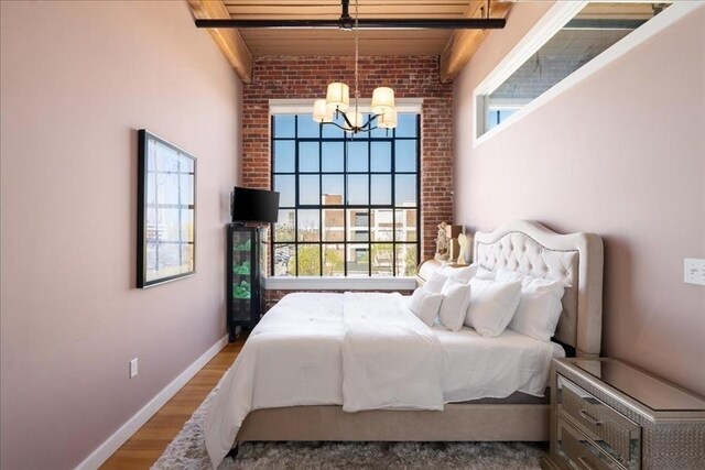 bedroom featuring baseboards, wood finished floors, and a notable chandelier