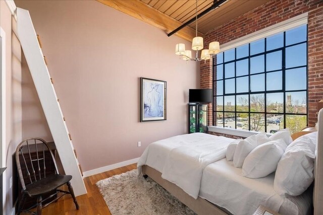 bedroom featuring wood ceiling, baseboards, brick wall, and a notable chandelier