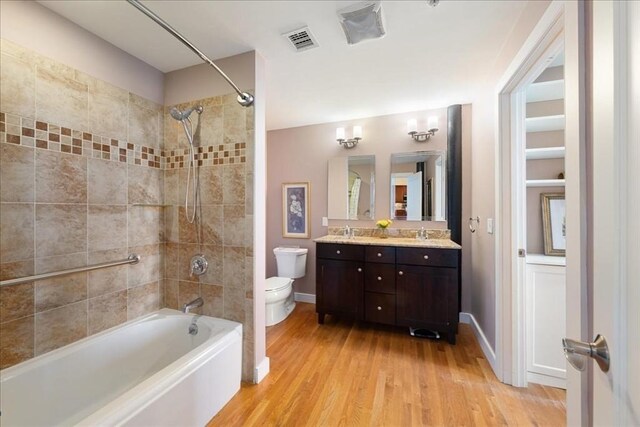 bathroom with visible vents, shower / tub combination, wood finished floors, and toilet