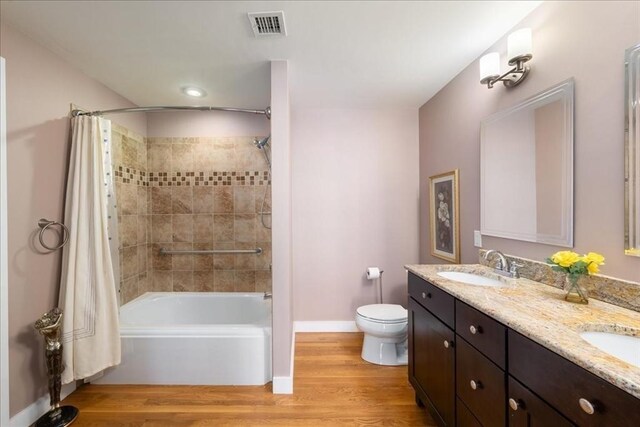 full bathroom featuring a sink, toilet, shower / bathtub combination with curtain, wood finished floors, and visible vents