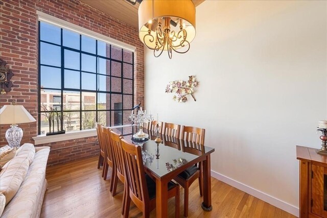 dining space with baseboards, a wealth of natural light, brick wall, and a notable chandelier