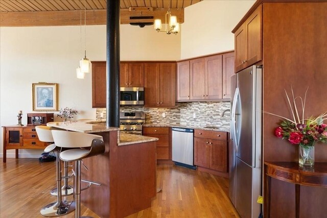 kitchen featuring light wood-style floors, brown cabinetry, wood ceiling, and appliances with stainless steel finishes