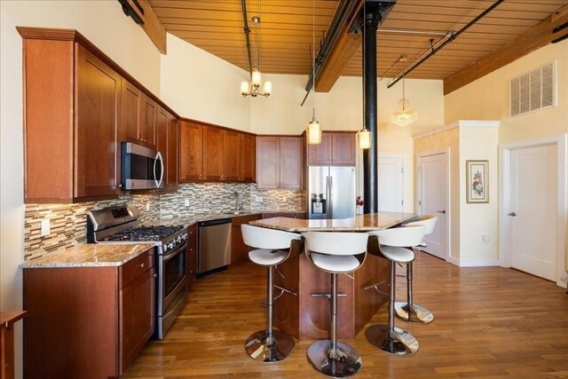 kitchen featuring wood ceiling, a breakfast bar area, a towering ceiling, visible vents, and appliances with stainless steel finishes