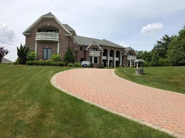 view of front of house with a balcony, a front yard, and brick siding