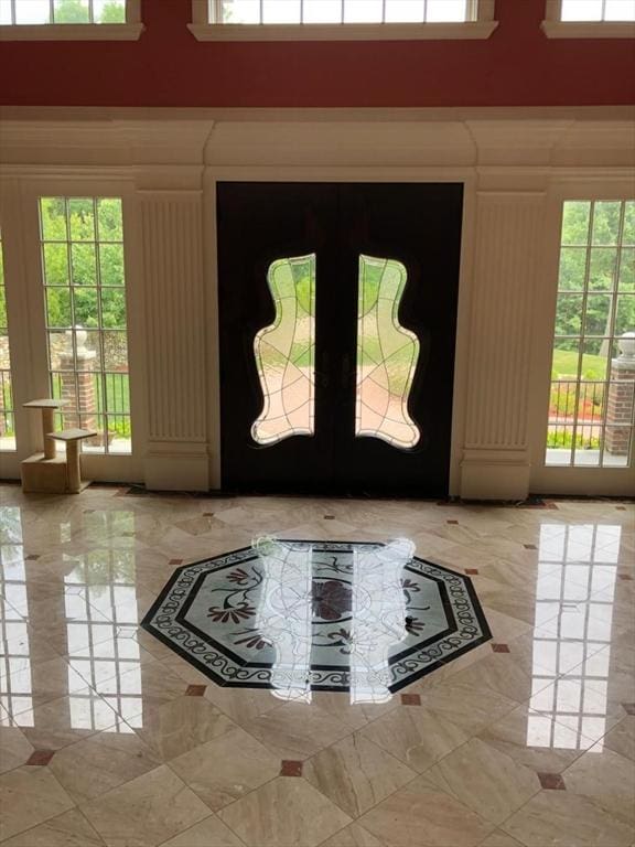 doorway featuring french doors, a healthy amount of sunlight, and a towering ceiling