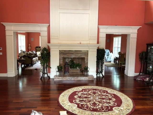 living room featuring a wealth of natural light, a high ceiling, wood finished floors, and a high end fireplace