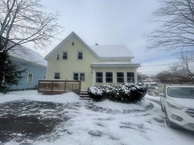 snow covered back of property with a deck