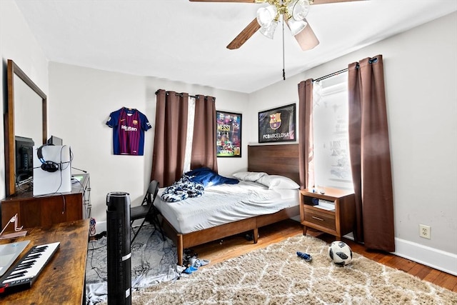 bedroom with a ceiling fan, baseboards, and wood finished floors