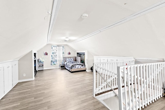 bedroom featuring lofted ceiling, baseboards, and wood finished floors