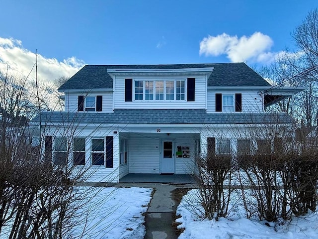 view of front facade with a shingled roof and covered porch