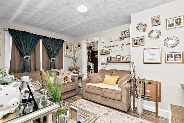 living room featuring a textured ceiling, baseboards, and wood finished floors