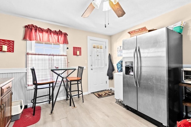 kitchen featuring a wainscoted wall, a ceiling fan, light wood-style floors, light countertops, and stainless steel fridge