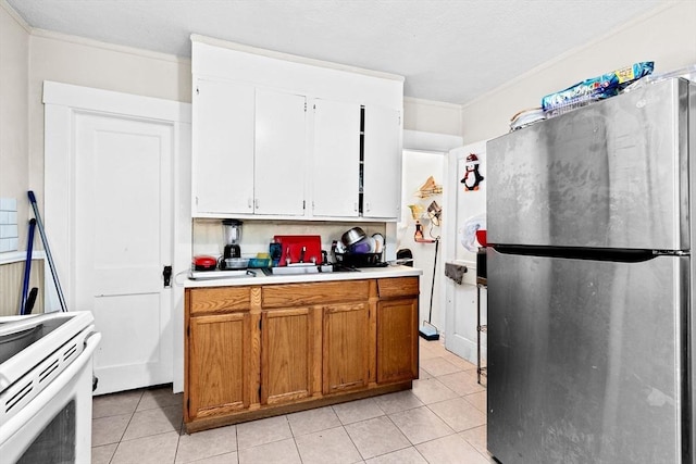 kitchen featuring light tile patterned floors, white range with electric stovetop, freestanding refrigerator, light countertops, and white cabinetry