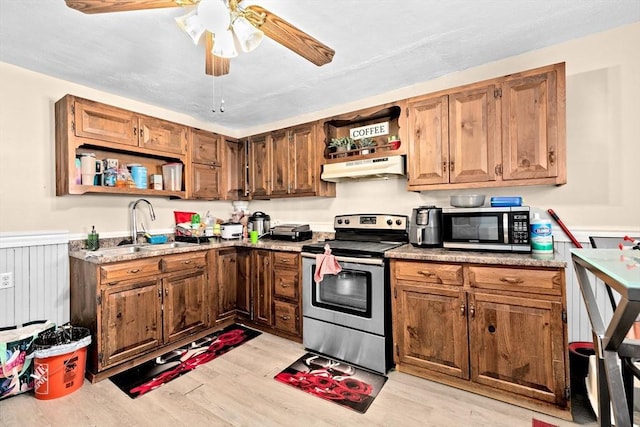 kitchen featuring under cabinet range hood, appliances with stainless steel finishes, open shelves, and a wainscoted wall