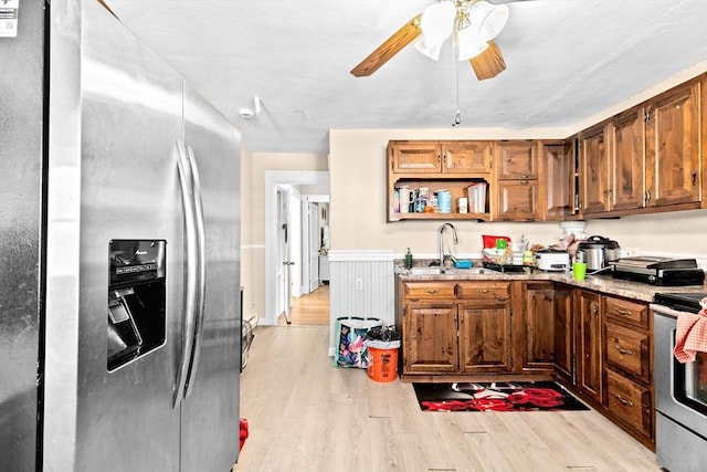 kitchen featuring brown cabinets, open shelves, stainless steel appliances, a sink, and light wood-type flooring