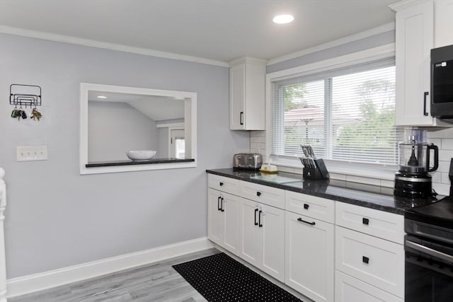 83 Chalmers St, Springfield, MA 01118 - kitchen featuring black range oven, backsplash, baseboards, white cabinetry, and recessed lighting