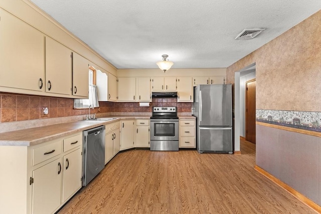 171 Duffy Dr, Taunton, MA 02780 - kitchen with appliances with stainless steel finishes, under cabinet range hood, cream cabinets, and light wood-type flooring