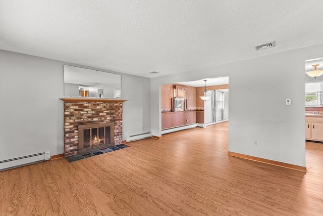 171 Duffy Dr, Taunton, MA 02780 - unfurnished living room featuring a textured ceiling, wood finished floors, a baseboard heating unit, and a fireplace