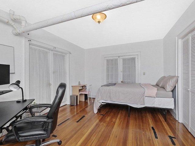 bedroom with an office area, wood-type flooring, and a closet