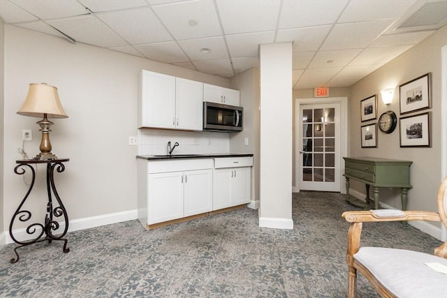 8 Crowninshield Unit 312, Peabody, MA 01960 - kitchen with dark carpet, stainless steel microwave, a paneled ceiling, white cabinets, and dark countertops