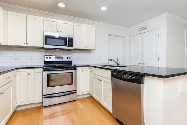 8 Crowninshield Unit 312, Peabody, MA 01960 - kitchen with appliances with stainless steel finishes, a sink, a peninsula, light wood finished floors, and dark stone countertops