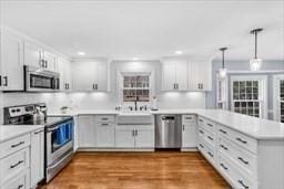 5 Hickory Rd, Southborough, MA 01772 - kitchen featuring appliances with stainless steel finishes, a peninsula, light countertops, pendant lighting, and white cabinets