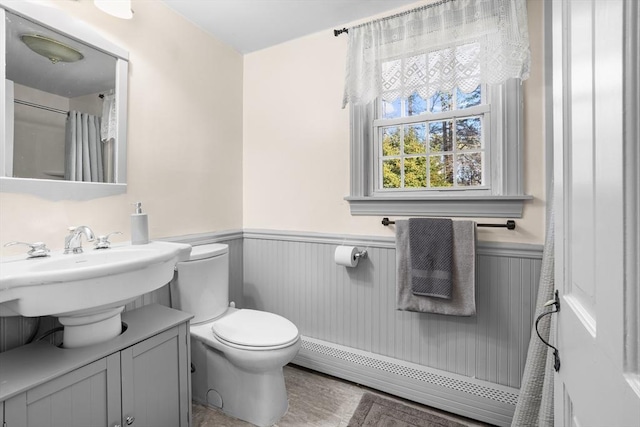 bathroom featuring toilet, vanity, and a baseboard heating unit